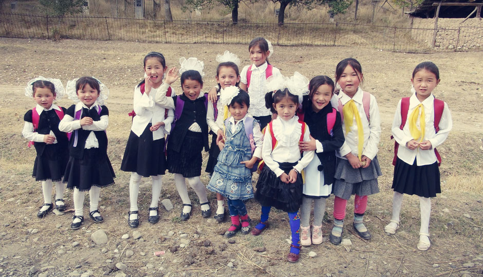 Kirgisische Schuluniform: Schwar-weiß, Schürzen und übergroße "Bommeln" in den Haaren